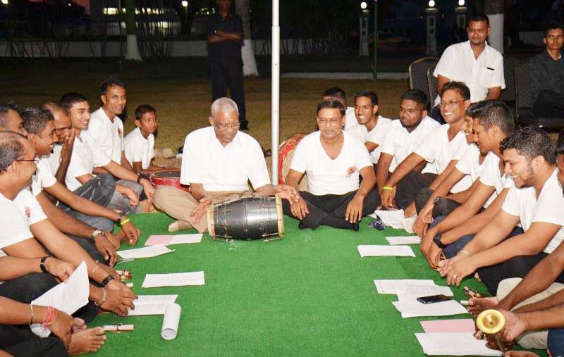 President David Granger tries his hand at the dholak [two-headed drum) during the Chowtal singing at State House 