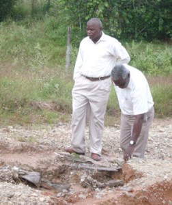 Minister Robeson Benn taking a closer look at the crater in the road