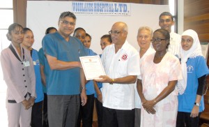  Dr Chatterpaul Ramcharran (fifth from right) hands  over the certification documents to Dr Neville Gobin 