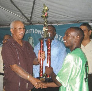 Banks DIH Managing Director Clifford Reis (left) handing  over the League's top trophy to captain of New Amsterdam United,  Colin Bowry. Also in photo from right: Carlton Joao, BFA Office  Manager Joseph Simon and Reginald Matthews (partly hidden). 