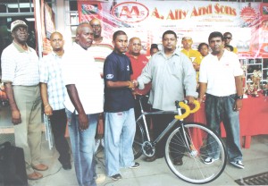 Managing Director of A. Ally & Sons Faizal Ally (2nd right) handing over the New Track Bike to Neil Reece. At center is Banks DIH Berbice Manager, Reginald Matthews.