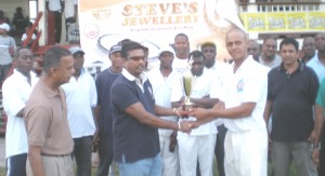 Captain of the victorious GNIC team Orin Hutson (right) receives the winning trophy from Steve’s Jewellery Steve Narine, while team-mates and officials look on yesterday. 