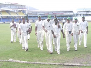 The Guyana players, wearing black ribbons on their shirt sleeves as a mark of respect for the late Janet Jagan, leave the field after taking first innings points from T&T at the ‘Oval’ yesterday.  Injured Steven Jacobs joins his happy Captain Travis Dowlin and teammates for this photo.