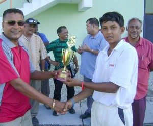 Man-of-the-Match Kevin Ramdeen (right)  receives his trophy from Guyana  Cricket Board Secretary Anand Sanasie  yesterday, at the Guyana National Stadium. 