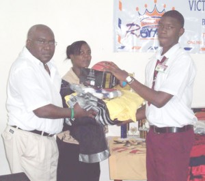 Regional Education Officer for Region 10, Marcel Hutson (left) hands over apparel to a student of New Silver City Secondary while Wanda Richmond looks on.