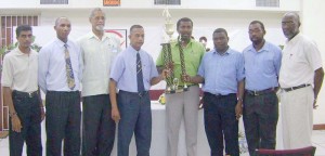 Bish Panday (centre, left) and Michael Cummings handing over the trophy to Alfred Mentore (centre) in the presence of representatives of GCA and UG including Vice Chancellor Vincent Alexander (right)