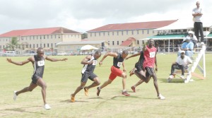 CLOSE CALL FOR SECOND!!! Michael Saul (right) points to the media after winning the Men’s 100m Final at the Police Sports Club Ground yesterday. From left, Keith Roberts, Kenneth Semple and Triston Joseph lean for second place consideration.