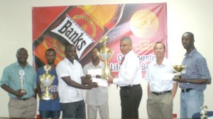 GFA General Secretary Marlan Cole (third left) receives the winning trophy and cash prize on behalf of BK Western Tigers from Banks DIH Sales and Marketing Executive Carlton Joao, while clubs representatives and Company officials look on.