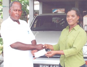 Mrs. Claudette Watts (right)  hands over the sponsorship cheque to the  Club Coach, Randolph Roberts.