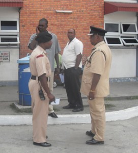 A relieved East Coast Divisional Commander, Balram Persaud (right) being briefed by another officer at the Georgetown Public Hospital following the slaying of Courtney James.