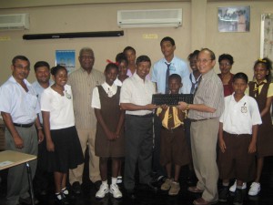  Happy moment: Students and teachers of various schools look on as Education Minister Shaik Baksh (sixth from left) collects a computer component from Food for the Poor Chairman Paul Chan-A-Sue.   