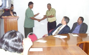 Commissioner of Forestry, James Singh presenting a  certificate to one of the participants, while Canadian High  Commissioner (acting) Brett Maitland and Minister Robert Persaud look on