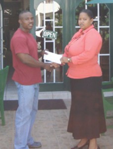 Aretha Campbell (right) handing over the cash donation to Randolph Morgan. 