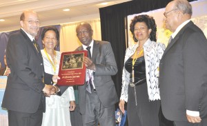 Anthony James (left) receiving his Hall of Fame Plaque from Austin Jack Warner in the presence of his mother centre.