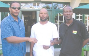Proprietor of the Windjammer Cuisine and Inn, Carey Harris (left) makes a  contribution to Lugard Mohan (centre) and Aubrey Younge yesterday.