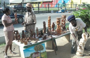 Two of the Rastafarian craft vendors display their products on Main Street to a potential buyer. 