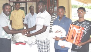 DCC President Alfred Mentore (left) presents US$100 to National Under-19 Vice Captain Royston Alkins, while Trevon Griffith, Totaram Bishun and other club members share the moment at the DCC pavilion on Monday afternoon. 