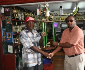 Mortimer Stewart (right) hands over the  Banks DIH trophy for the 2-year-old event to Compton Sancho at the Trophy Stall yesterday. 