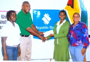 (Left to right) - President of GUYBCA Mark Harper (left) receives the cheque from Communications and Public Relations Officer Jonelle Dummett, while Rendy Murray (left) and Treasurer of GUYBCA Theresa Pemberton appreciate the moment. 
