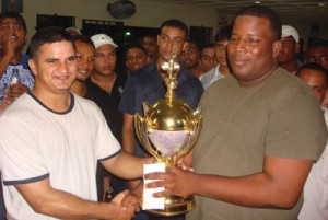 Anthony Xavier (left) receiving his cash and trophy from a  Banks DIH representative in the presence of excited supporters. 