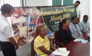 Two Amerindian work-study students hold up an Amerindian  Heritage Month banner as officials announce plans for the celebrations.  From left are Yvonne Pearson, Chairperson of the National Toshao Council; Pauline Sukhai, Minister of Amerindian Affairs; Dr Frank Anthony,  Minister of Culture, Youth and Sport; and Nigel Dharamlall,  Permanent Secretary in the Ministry of Amerindian Affairs. 