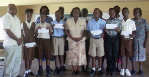 Mrs Paulette Charles poses with the top students and their teachers after they were presented with the awards. At left is Canada-based George Culley of the Committee to Assist Buxton.