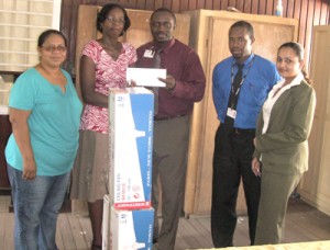 Headmistress (ag.) Donna Williams receiving the cheque and ceiling fans from Scotiabank representatives 