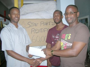 Cush’s sibling, Trenton (right),  presents Holland with the sponsorship  check while an employee looks on.
