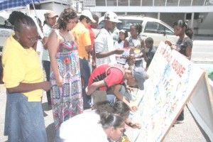 Minister of Human Services and Social Security, Priya Manickchand-Murli looks on as children participate in painting signs on Main Street, Georgetown to mark the end of Child Protection Week.