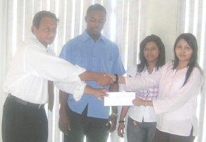 Peter Abdool (left) accepts the check from Akbar Auto Sales representative, Ravera Haroon (right), while Bebi Shazeeda Alli (2nd right) and Carwyn Holland looks on. 