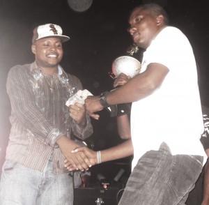 Mr. Digicel Hype 2009 DJ Puffy (left) collects his $200,000 first prize from a WildFire Productions representative. 