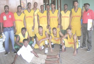 WE ALMOST DID IT!!! Guyana’s national junior basketball team pose with Coach, Robert ‘Bobby’ Cadogan and Statistician Dennis Clarke at the Anthony Nesty Sports Hall in Suriname yesterday after narrowly missing the IGG Basketball title.