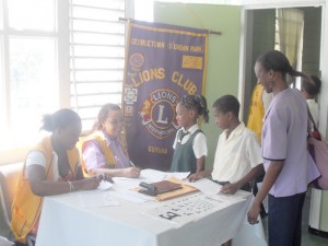 Teachers aiding children in being registered by lions club members