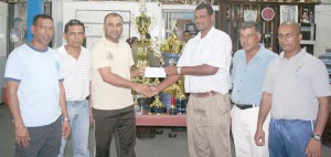 Organiser of GSL Leonard Harriprashad receives cheque from  Ricky Deonarain (left) of 4R, while executive members of Floodlights team  (from left) Ramesh Sunich, Rahaman Khan, Mike Singh and Reaz Hussain look on.