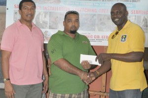 First time on board!!! A&J Carpet House Proprietor Ravi Persaud (centre) hands over cash to Aubrey ‘Shanghai’ Major. At left is Kashif Muhammad. 