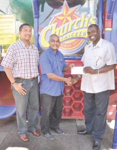 hurch’s Chicken Director of Operations Gregory De Gannes (centre) handing over the cheque to K&S Director Aubrey ‘Shanghai’ Major. Fellow Director Kashif Muhammad shares the moment.