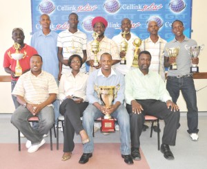 Alpha United Captain Howard Lowe (seated 2nd right) pose with the Cellink Premier League championship trophy. Also in front row from right, Wyston Robertson (GT&S Director of Marketing) Rhonda Johnson (GT&T Marketing) and Troy Mendonca (GFA President). Standing from left, Marlon Washington (GDF) Lyall Gittens (GFA), Ronson Williams, Sampson Gilbert (Sunburst Camptown), Wayne St. Jules (Fruta Conquerors) Lester Sealy (GFA) and Shawn Bishop.   