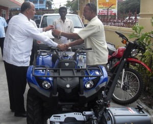 Minister Clement Rohee hands over the keys for the ATV  to an executive of the Bartica Community Policing Group.