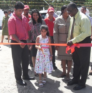 Little Aliah Sarah Mohamed is flanked by her  parents and Sol officials as she cuts the ribbon