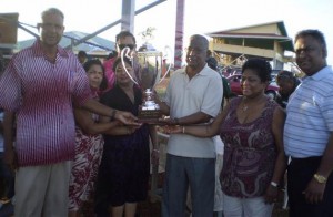 In picture Kublall Ramnarayan eldest son of Deo Kharag is assisted  by other family members as they hand over the Deo Kharag Memorial  trophy to President of the Kennard Memorial Turf club, Roopnarine Matadial ‘Shines’. Looking on are Justice Cecil Kennard with dark shares and Ron Ramnarayan manager of Metro at right.