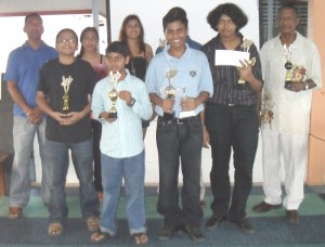 Taffin Khan (2nd right) displays his winnings along with Errol Tiwari (right) and Muesa (hidden on Khan’s right). Others in photo are Sunesh’s daughter and wife (2nd and 3rd left back row) along with the three junior players.