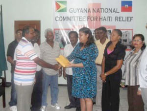 Representative from the Wakenaam NDC makes  the donation to the chairman of the Haiti Relief Fund and  Minister of Human Services Priya Manickchand 