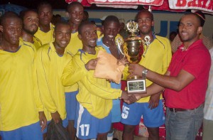 Eon DeVieira of Macorp (right) hands over the cash prize and trophy to  Pele skipper Travis Grant, while his teammates enjoy the moment. 