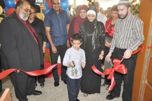 Naeem Nasir Jnr, cuts the ceremonial ribbon as his sister Anesa,  his father Naeem Nasir, President Bharrat Jagdeo and others look on. 