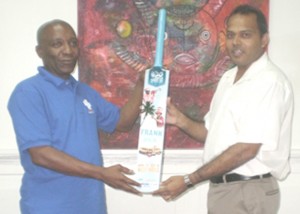 ICC World Twenty20 West Indies Tournament Director, Mr. Robert Bryan (left), presents Sports Minister, Dr. Frank Anthony, with a personalized “Bring It” bat.