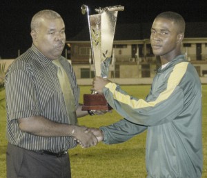 A RARE SECOND BEST IN ATHLETICS!!! Guyana’s junior national thrower, Michael Bowman (left) accepts the second place athletics trophy from Cayenne’s City Hall representative for sports, Jean Laquitaine Sunday night.