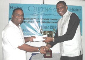  Mr. Roger Harper (right) collects a cheque and trophy from proprietor of Queensway, Mohamed Qualander, for the GCA 40 overs 2nd Division tournament later this year.