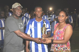 Tournament MVP Mark Liddell (centre) collets his trophy from Parliamentary Secretary Steve Ninvalle (left) and Mrs. Haynes. 