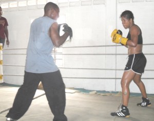 Coach Sebert Blake (left) gives instruction as Alfred prepares to hit the hand pads during training sessions yesterday morning. 
