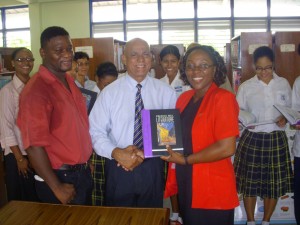 Former President of the Rotary Club of Georgetown, Affeeze Khan, hands over one of the literature books to Secondary Coordinator of Marian Academy, Cheryl Andrews while Rotarian, Gary Thompson (left) looks on in the presence of other teachers and students from the school yesterday.
